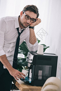 从办公室机器上倒咖啡的商人图片