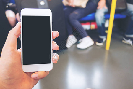 在地铁中手持白色手机黑屏为空白的黑屏幕与许多背景人混在一图片