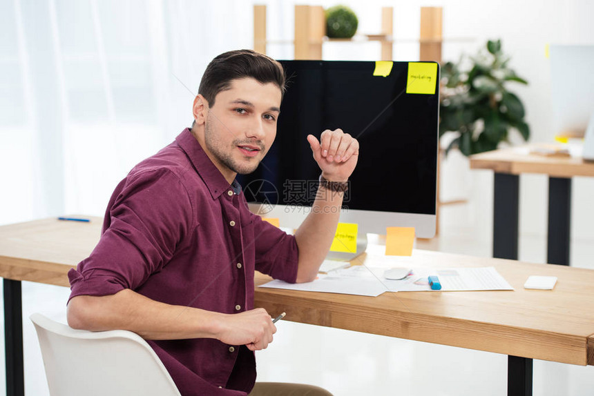 年轻营销经理在办公室用空白计算机屏幕看工作场所的照相机图片