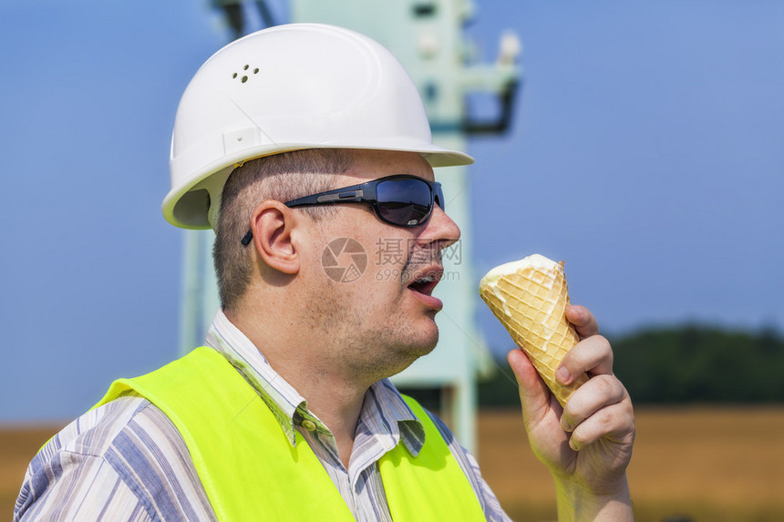 在蓝天背景下吃冰淇淋的工人图片