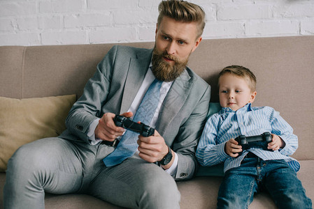 商人和小儿子在家一起玩电子游戏工作和图片