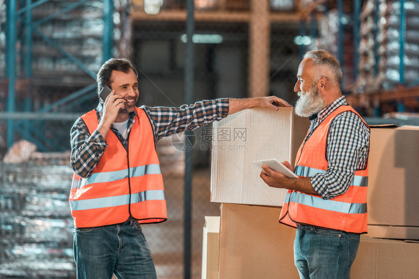 两名男工人在仓库工作时使用数字设备图片