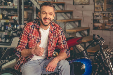 穿着休闲服的帅哥在修理店里坐在摩托车上图片