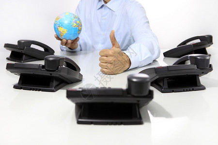 全球和类似的手与办公桌上的办公电话全球图片