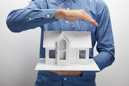持有灰色保险概念小型住房模型的男图片