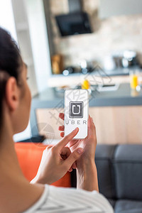 在厨房屏幕上使用带有uber标志的智能手机的妇女有高清图片