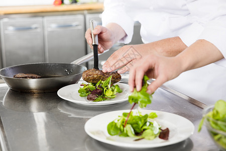 厨师和他的助手在餐厅或旅馆的专业厨房里准备新鲜沙拉菜背景图片