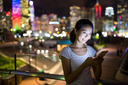 亚洲年轻女子晚上看手机图片