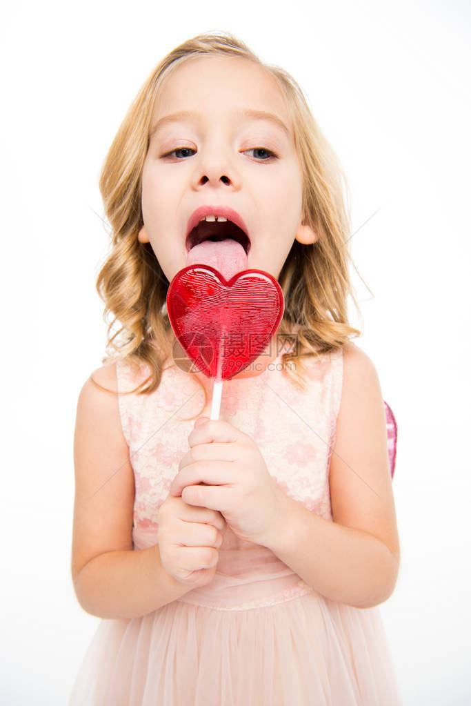 穿粉红裙子的可爱小女孩吃着心形棒糖图片