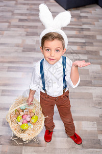 小兔子耳朵里的小男孩拿着一篮子的复活节彩色鸡蛋图片