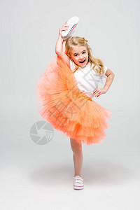 穿着礼服的快乐小女孩做拉伸戏法看着白背景图片