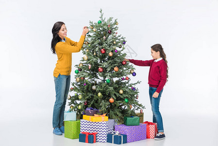 妈笑着的妈和女儿一起装饰圣诞树与玻璃球图片