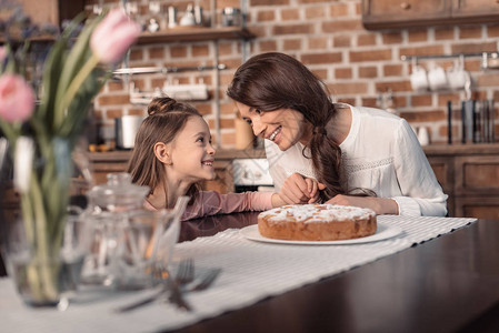 快乐的母亲和女儿的肖像蛋糕在桌上母亲图片