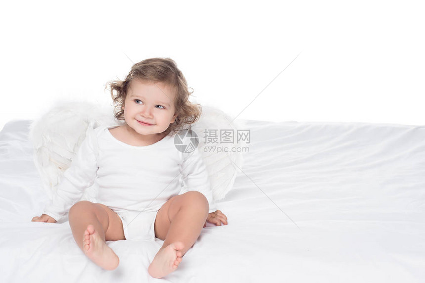 可爱笑的婴儿有翅膀坐在床上图片