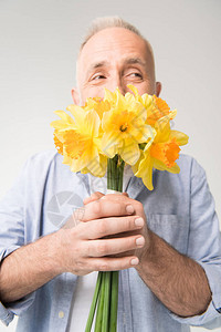 快乐的老人拿着花水仙子的花束图片