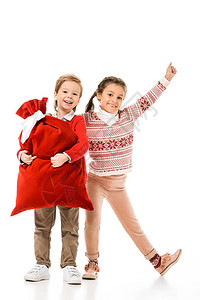 带着圣诞老人礼物袋的兴奋小孩子们看着在白色上图片