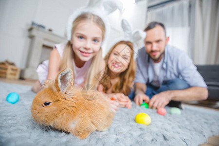 家庭在家里躺在地毯上玩兔子蛋和复活节鸡图片