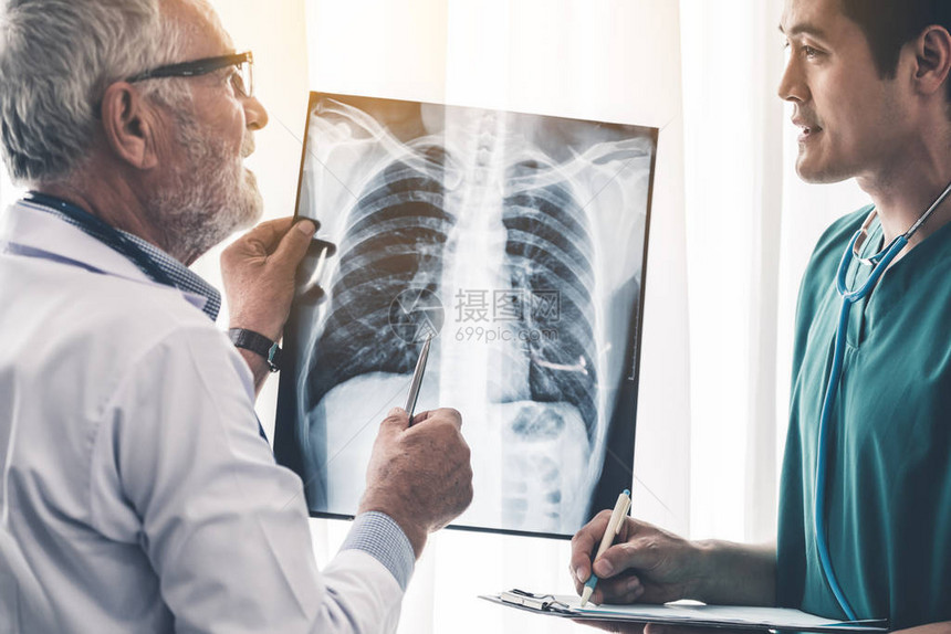 高级男医生在医院与另一位医生时查看患者胸部受伤的X光片医疗保健人图片