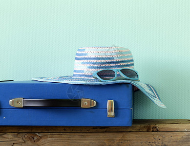古老的蓝色行李箱旅行和帽在绿图片