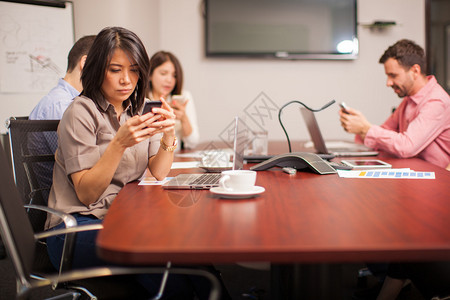 一群人在会议室里用手机发短信和社交网图片