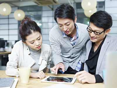 一群年轻的亚洲企业家在办公室使用平板图片