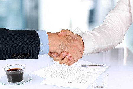 在签署合同的两名同事之间密切握手的画图片