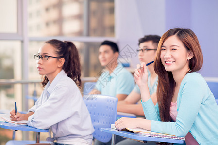 一个快乐的年轻学生的肖像笑着看前方的图片