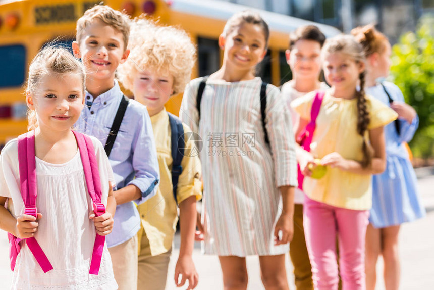 一群可爱的学童站在校车前排成一排图片