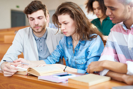 认真集中的年轻同学坐在大学课桌前图片