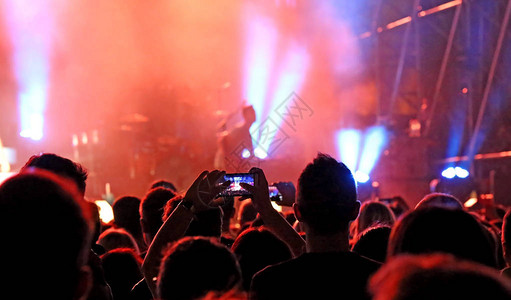 在摇滚乐队现场音乐会中用现代智能手机拍摄和录制视频的图片
