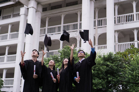 一群成功的学生一起祝贺他们将毕业帽扔在空中并庆图片