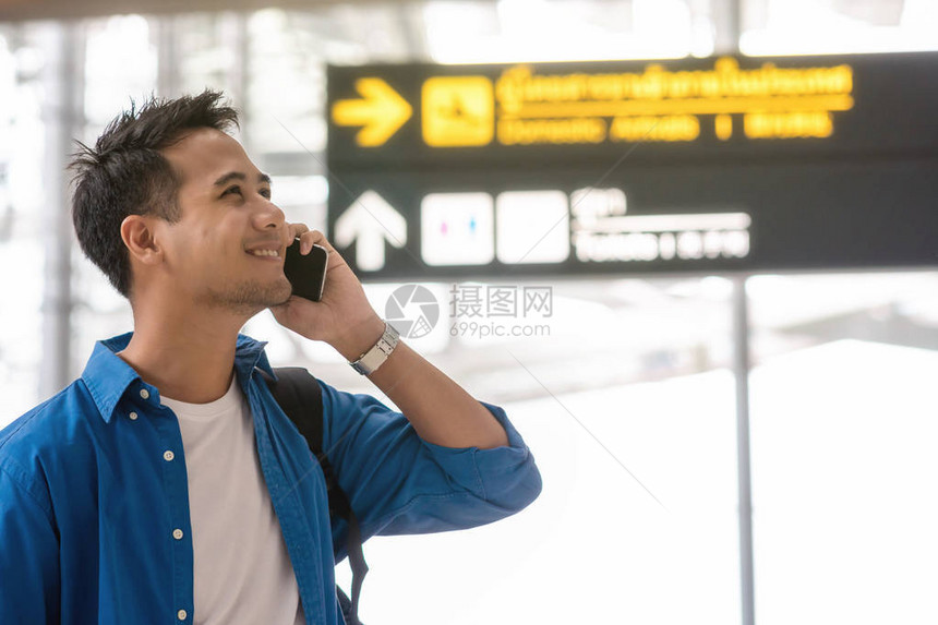 亚洲旅客使用智能手机在现代机场打电话图片