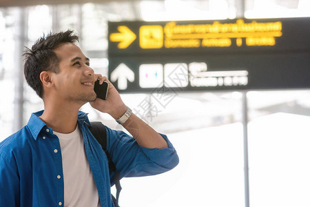 亚洲旅客使用智能手机在现代机场打电话图片