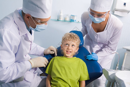 可爱男孩在口腔检查前与牙医及其助图片