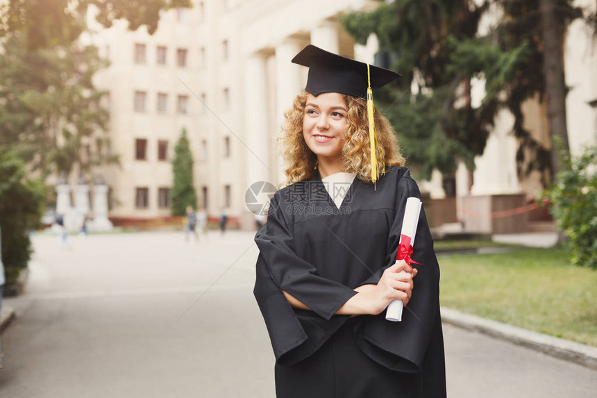 年轻微笑的女人在大学毕业那天持有文凭教育资图片