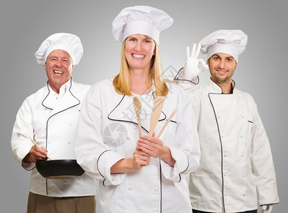 一群快乐的厨师在灰色背景下工作图片