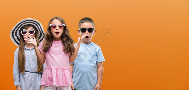 一群橙色背景中的男孩和女孩惊恐地惊恐地脸色惊恐图片