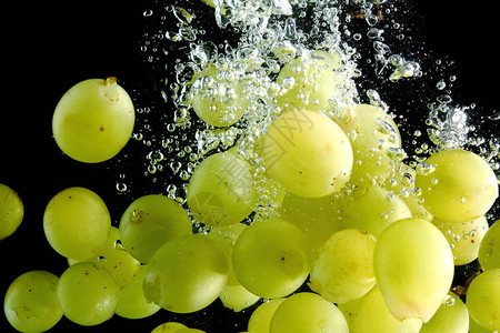 黑色背景下落水的绿葡萄高清图片