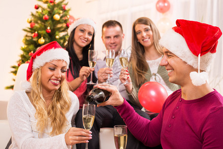 庆祝圣诞节或新年的快乐朋友在家里用香槟杯庆祝图片
