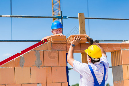 两名瓦工或建筑工人或工人在建筑或建筑工地上建造或砌砖或铺图片
