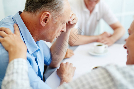 担心的老人在聚会期间与同伴分享他的烦恼或恐惧图片