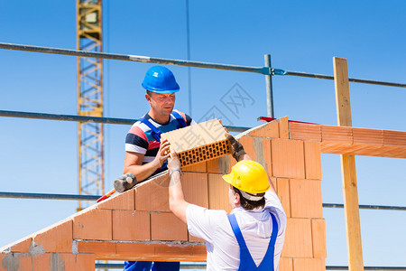 两名瓦工或建筑工人或工人在建筑或建筑工地上建造或砌砖或铺背景图片