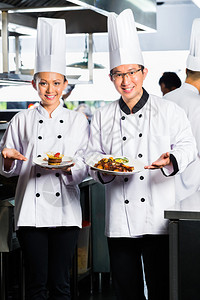 亚裔印度尼西亚厨师和其他厨师一起在餐馆或旅馆做商业厨房烹饪图片