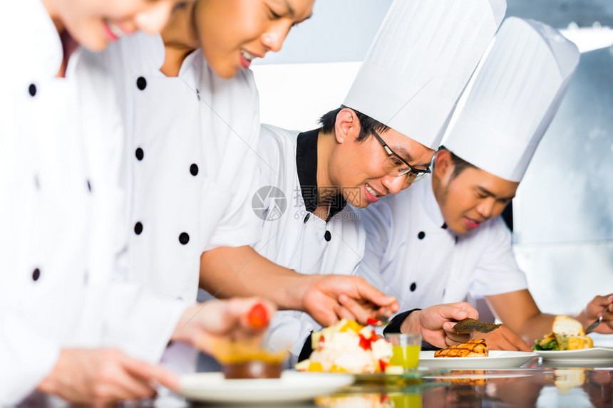 亚裔印度尼西亚厨师和其他厨师一起在餐馆或旅馆做饭烹饪最后菜图片