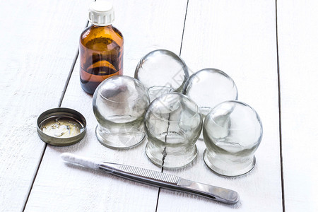 旧的医用杯子泡中的酒精汽油和在白色木制桌面上加棉润滑剂的树脂图片