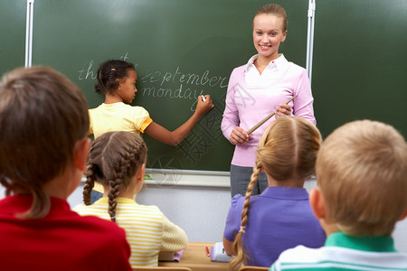 女孩在黑板上写字时学生坐在课中看着图片