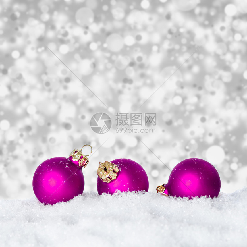 雪中的紫色圣诞节球带有bokeh图片