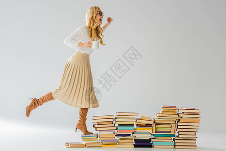 成年时尚女人站在书本上拿着白色杯子图片