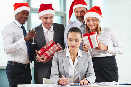 严肃的女员工与一群准备圣诞惊喜的同事一起分图片