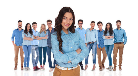 自信的年轻女站在她身穿蓝衬衫手交叉着双手的白背景临时小组前图片